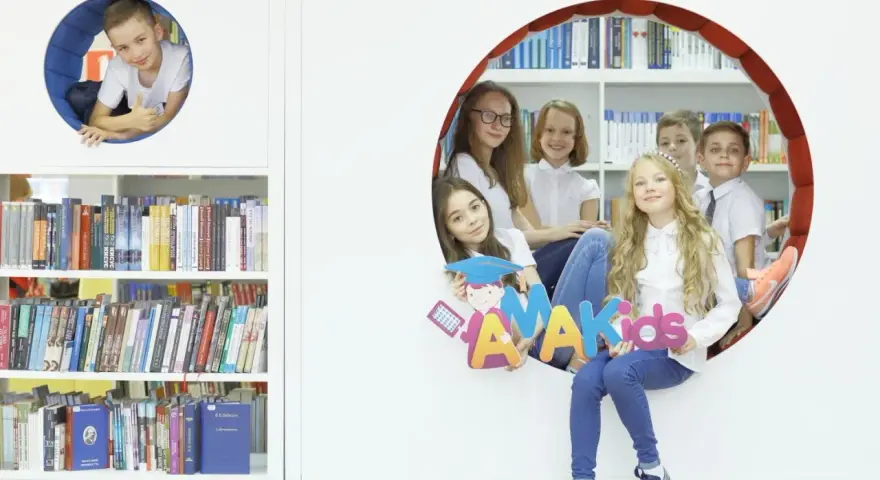 Dzieci z radością pozują z literami "AMAKids" w bibliotece.