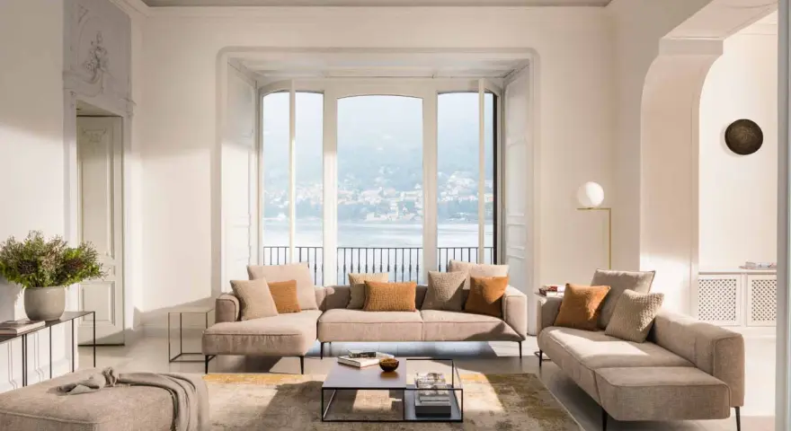Un salon cocooning chaleureux avec un grand canapé d'angle, des coussins douillets et une vue imprenable sur un lac.