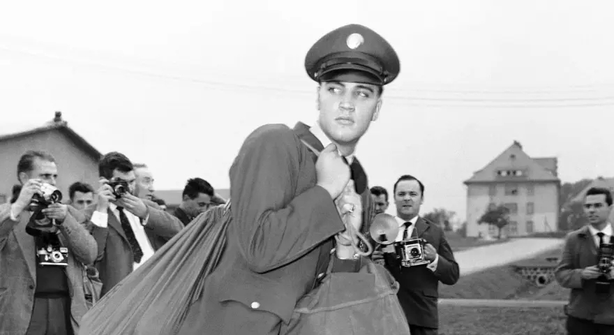 Elvis Presley 1958, in Uniform, wird von Paparazzi umringt, die mit ihren Kameras auf ihn richten.