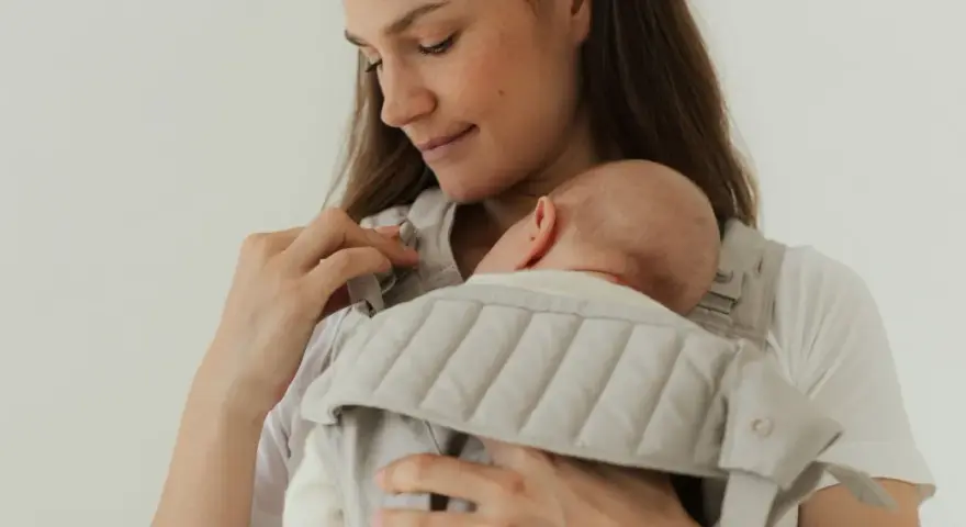Mutter hält ihr Neugeborenes in einer Trage. Die warme Kleidung neugeborene winter schützt das Baby vor Kälte.