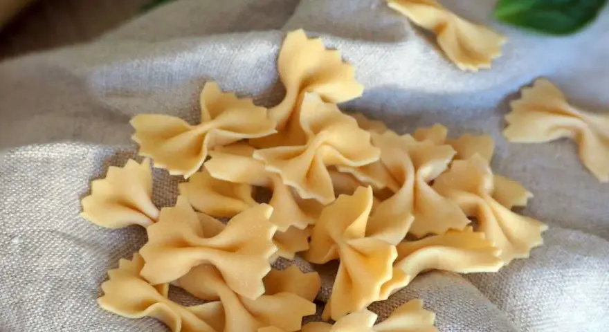 Farfalles fraîches, prêtes pour une délicieuse recette pâte maison. Une feuille de basilic ajoute une touche de couleur.