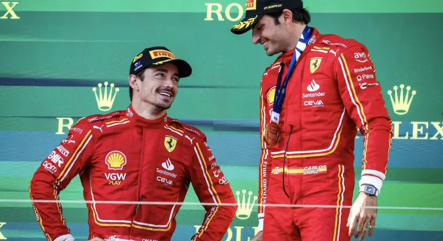 Carlos Sainz, con su altura destacada, sonríe en el podio junto a su compañero.