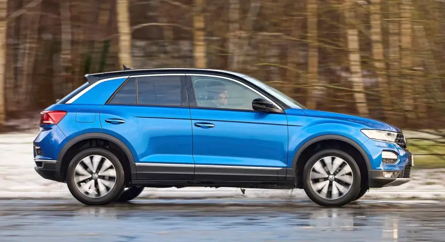 Blauer VW T-Roc fährt durch verschneite Landschaft. Keine Rede von vw t-roc kinderkrankheiten, nur Fahrspaß!