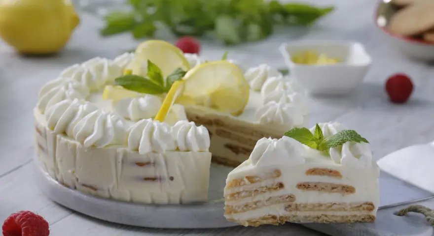 Pastel de limón con crema batida, rodajas de limón y menta.