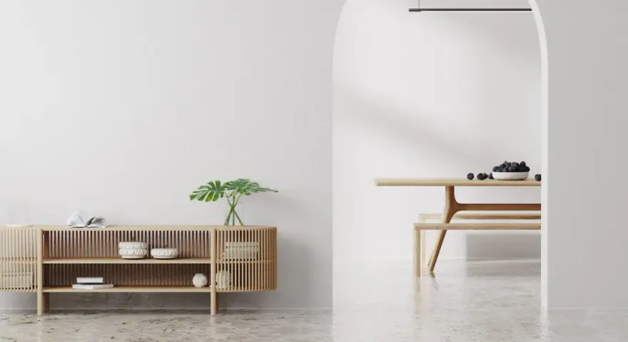 Un espacio minimalista con un aparador de madera y un comedor. Las paredes lisas y el suelo pulido crean un ambiente sereno.