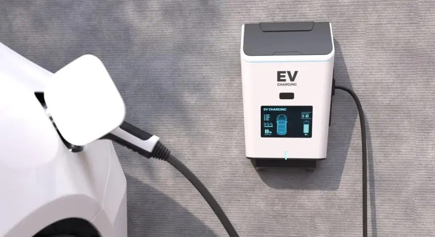 Biały samochód elektryczny podłączony do ładowarki EV na ścianie.