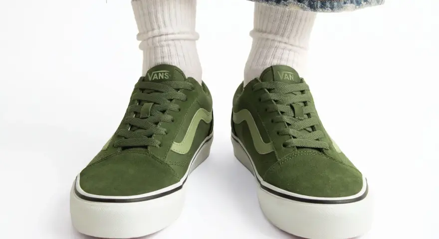 Zielone trampki Vans z jasną falą. Czy to rozmiar buta 11.5 cm? Białe skarpetki i podarte jeansy dopełniają stylizację.