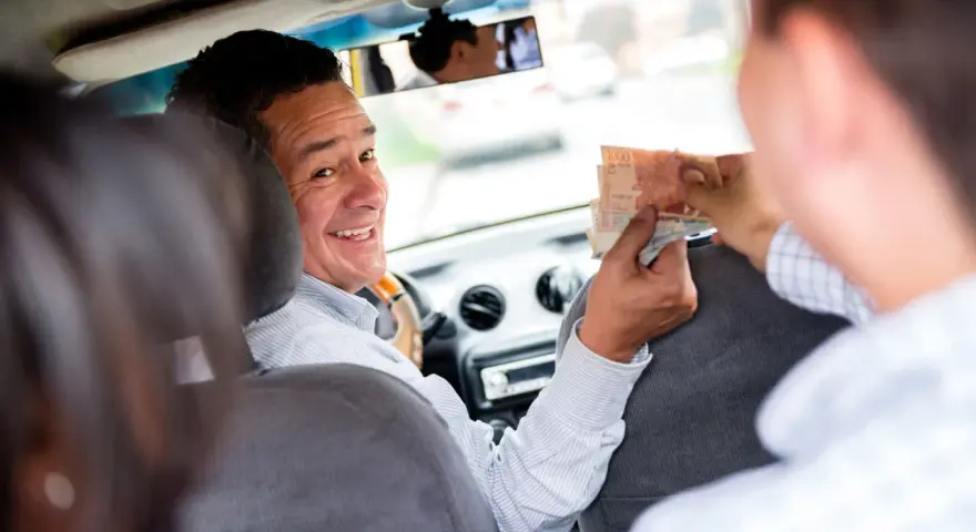 Ein Taxifahrer lächelt und nimmt Geld entgegen, ein Zeichen für ein gutes Taxi Trinkgeld.