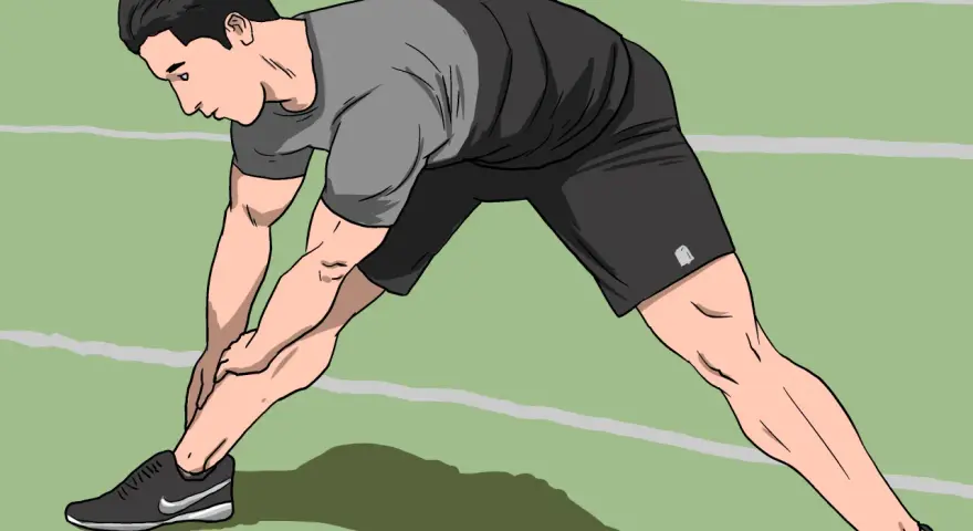 Man stretching his legs on a green indoor track, preparing for an intense indoor sprint workout.