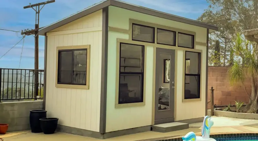 A modern shed, perfect to build a backyard oasis, sits by a pool with a unicorn float.