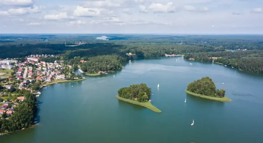Malownicze jezioro z wyspami i żaglówkami, otoczone lasem i zabudowaniami. To widok, który potwierdza, że to jedne z najpiękniejszych jezior w Polsce.