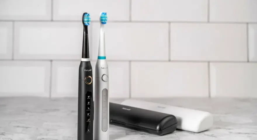 Dwa eleganckie modele szczoteczek sonicznych, czarny i srebrny, z różnymi końcówkami do wyboru. Obok etui podróżne.
