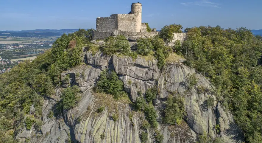 Zamek Chojnik, dawniej znany jako zamek Jelenia Góra, majestatycznie wznosi się na skalistym szczycie, otoczony bujną zielenią lasów.