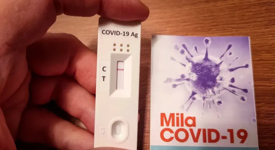 Szybki test antygenowy COVID-19 z jedną kreską kontrolną. Obok opakowanie z grafiką wirusa.