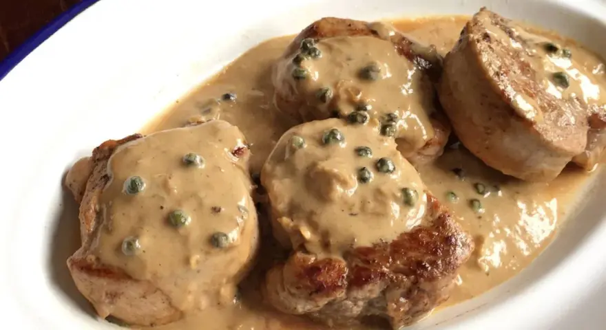 Cuatro medallones de solomillo a la pimienta en una cremosa salsa con granos de pimienta verde.