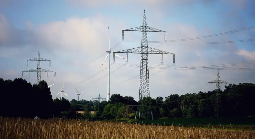 Wiatraki i linie energetyczne na tle nieba. OZE w Polsce to przyszłość, która już dziś zasila nasze domy.
