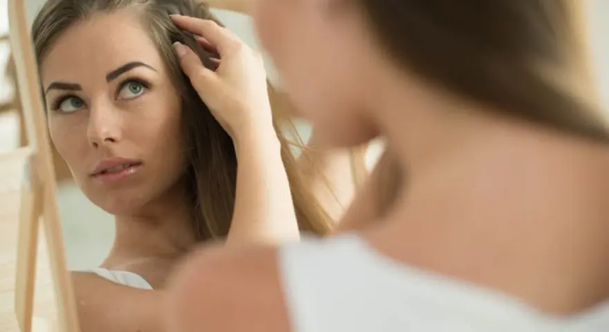 Besorgte Frau prüft im Spiegel ihr Haar, möglicherweise wegen Haarausfall in der Schwangerschaft.