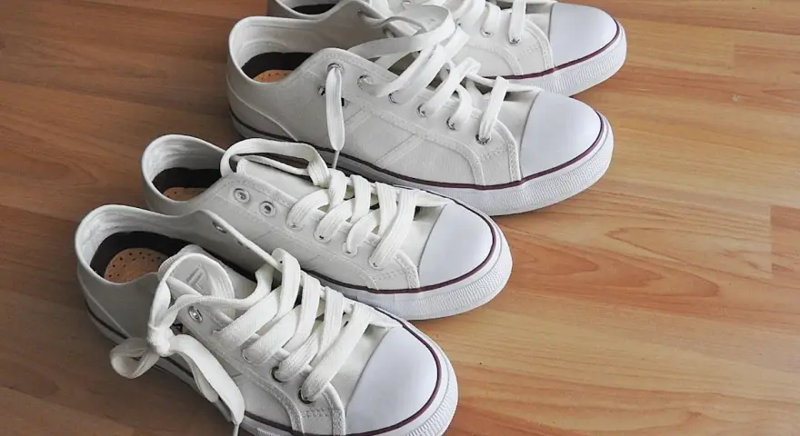 Cuatro zapatillas blancas de lona, listas para limpiar y lucir impecables.