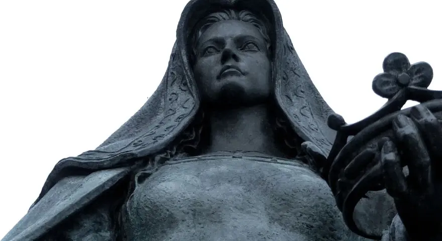 Statue de Jeanne la Folle, voilée, tenant une couronne de fleurs. Son regard est tourné vers le ciel.