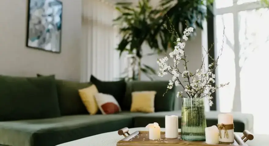 Zielona kanapa, świece i kwiaty na tacy tworzą harmonię w stylu feng shui.