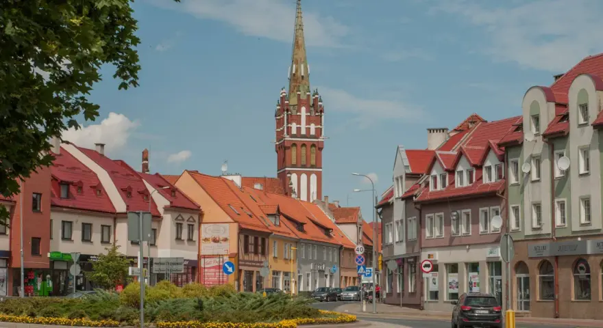 Kętrzyn atrakcje: malowniczy rynek z charakterystyczną wieżą kościelną, kolorowe kamienice i zielone skwery.