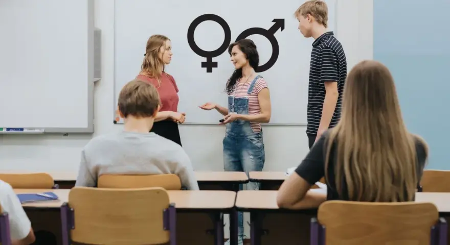 Lekcja edukacji seksualnej w klasie. Nauczycielka omawia symbole płci z uczniami.