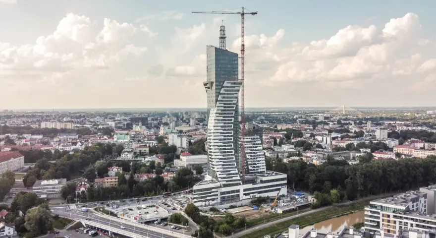 Wielka, kręcona wieża góruje nad miastem. To najwyższy budynek mieszkalny w Polsce, wciąż w budowie, z dźwigiem na szczycie.
