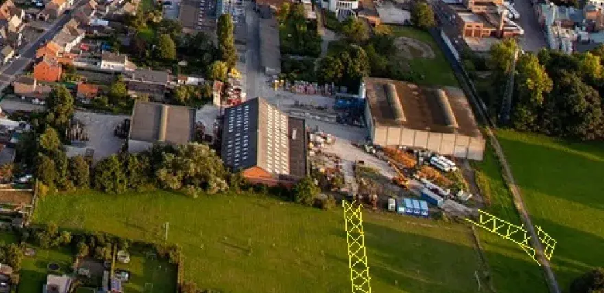 Vue aérienne d'un lotissement et d'une zone industrielle. Un pylône jaune est visible, marquant un emplacement réservé pour le droit de délaissement.