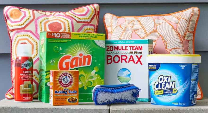 Supplies for how to clean outdoor cushions: Scotchgard, Gain detergent, Borax, baking soda, OxiClean, and a scrub brush.