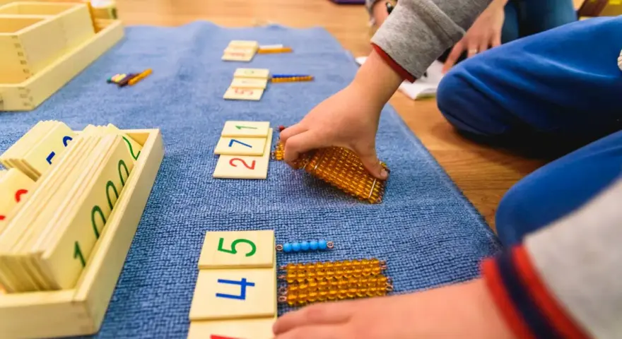 Dzieci bawią się koralikami i kartami z cyframi, ucząc się matematyki.
