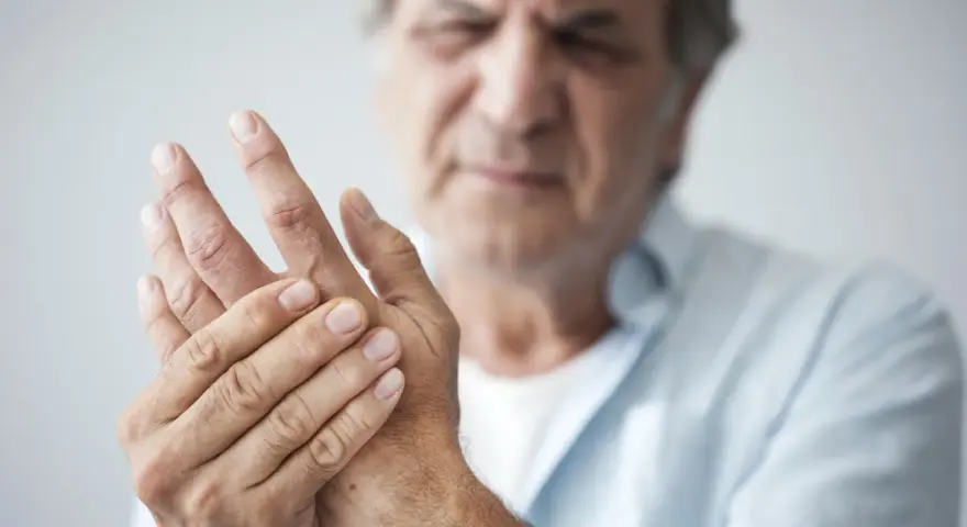 Mann hält seine Hand, da seine Finger schmerzen beim Beugen.