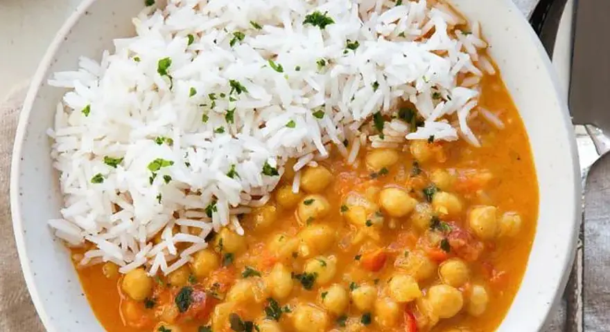 Un delicioso curry de garbanzos con arroz blanco esponjoso, espolvoreado con perejil fresco.