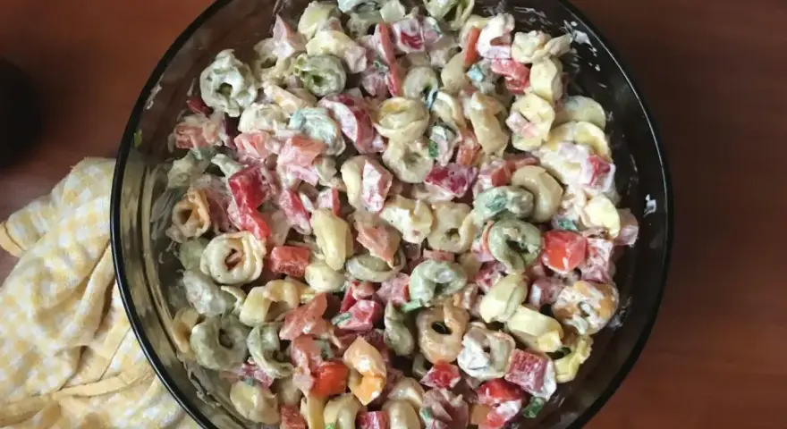 Kolorowa sałatka z tortellini, papryką i majonezem w szklanej misce.