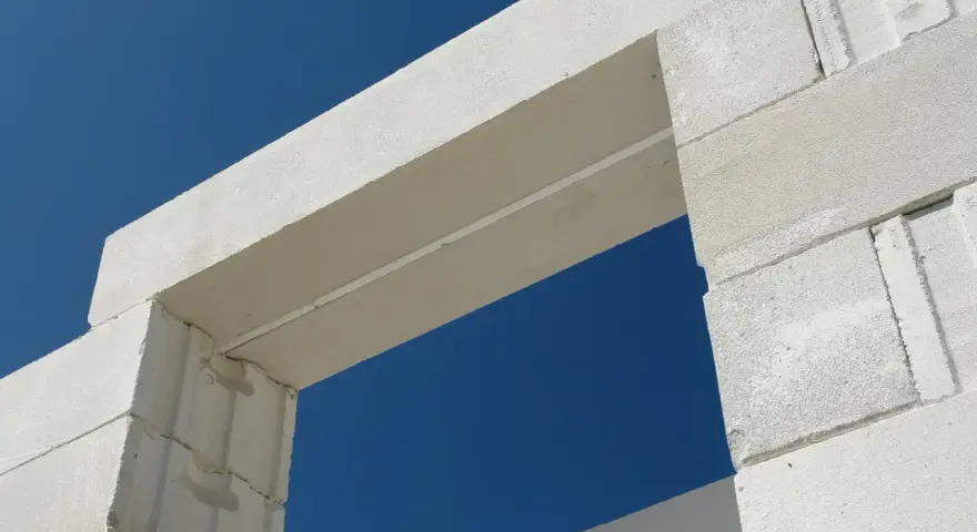 Białe nadproże nad drzwiami 90, wykonane z bloczków z betonu komórkowego, na tle błękitnego nieba.