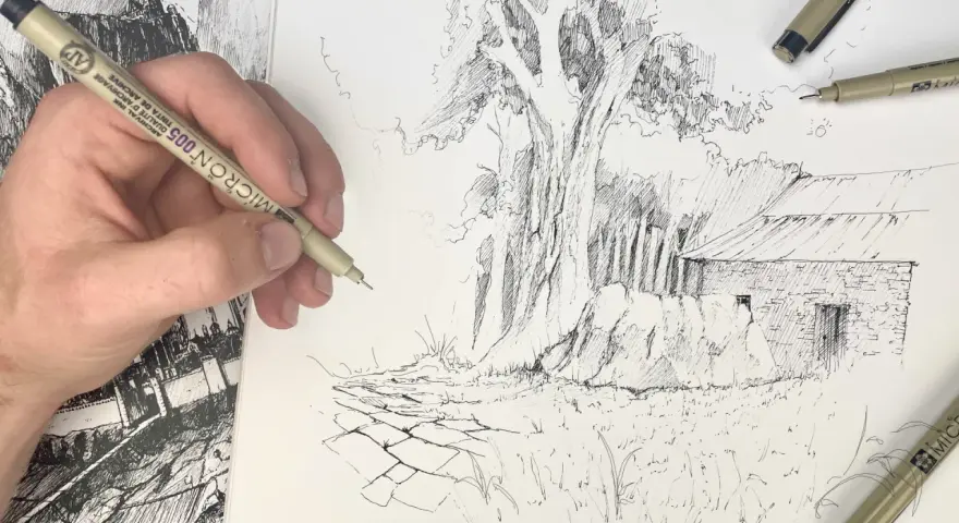 Main d'artiste esquissant une scène rurale avec un gros arbre et une grange. La texture du dessin facile est rendue par des traits fins.