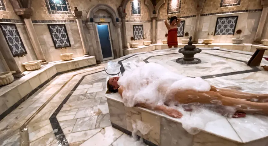 Kobieta w pianie w łaźni hammam. To tradycyjne tureckie łaźnie parowe, miejsce relaksu i oczyszczenia.