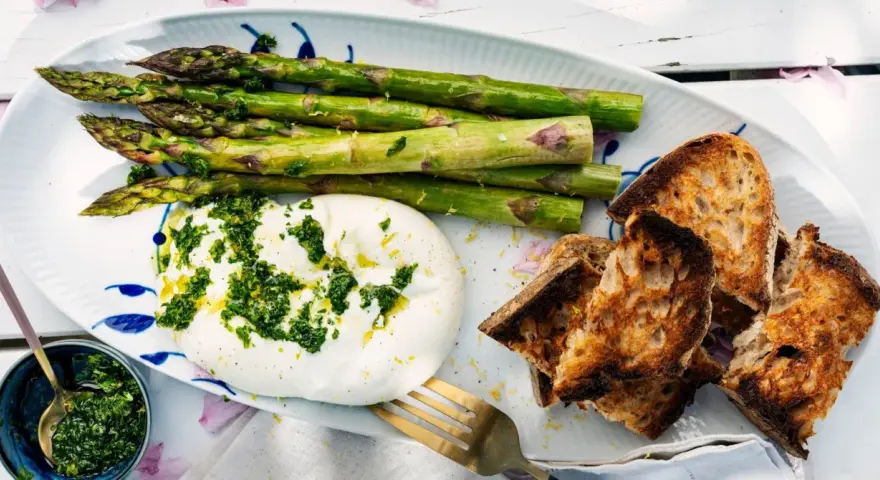 Burrata med sparris och rostat bröd, toppad med en fräsch gremolata. Perfekt för ett lätt sommarmål.