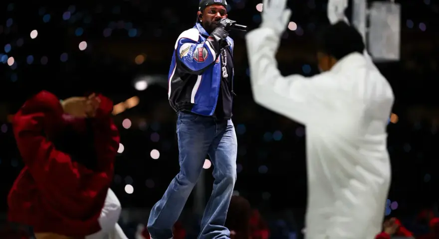 Un rappeur sur scène, micro en main, devant une foule lumineuse. Une performance qui rappelle l'énergie du rap francais.