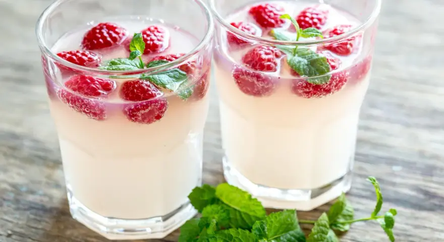 Dwa orzeźwiające drinki z limoncello, malinami i miętą na drewnianym blacie. Idealne na letnie popołudnie.