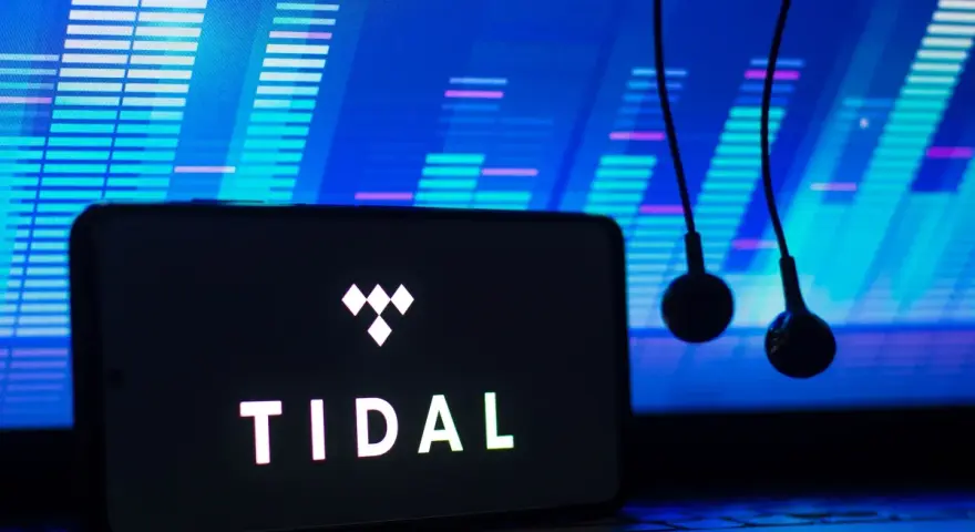 Smartfon z logo TIDAL i słuchawkami na tle ekranu z wizualizacją dźwięku.