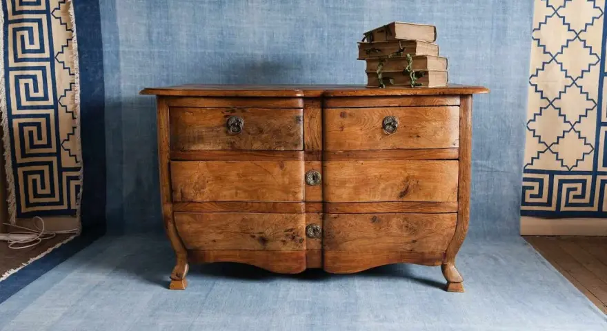 Cómoda de madera antigua, lista para pintar. Unos libros viejos descansan sobre ella.