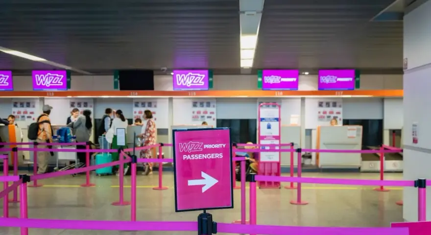 Kasa Wizz Air, gdzie pasażerowie dokonują self check-in. Różowe taśmy wyznaczają kolejkę do stanowisk odprawy.