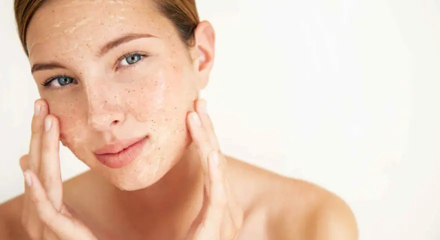 Mujer aplicándose una mascarilla exfoliante con vinagre de manzana para la cara. Sus dedos masajean suavemente el producto.
