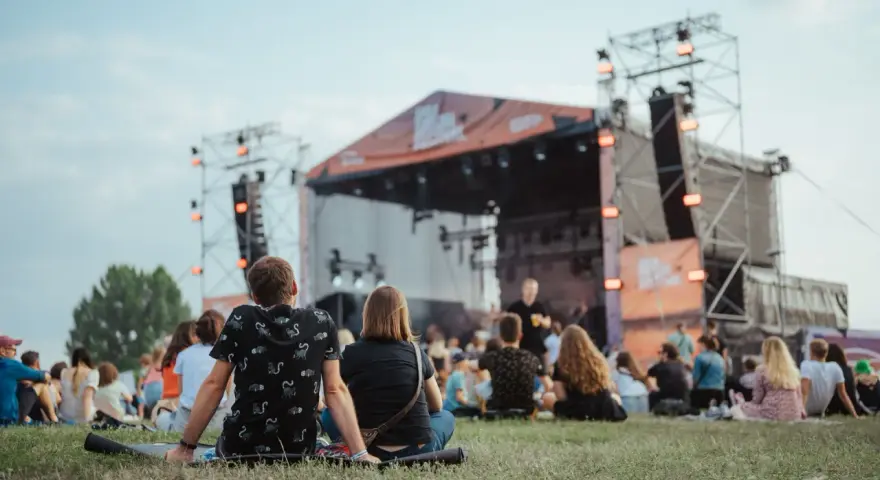 Widownia siedzi na trawie przed sceną podczas Enea Festival Baranowo.