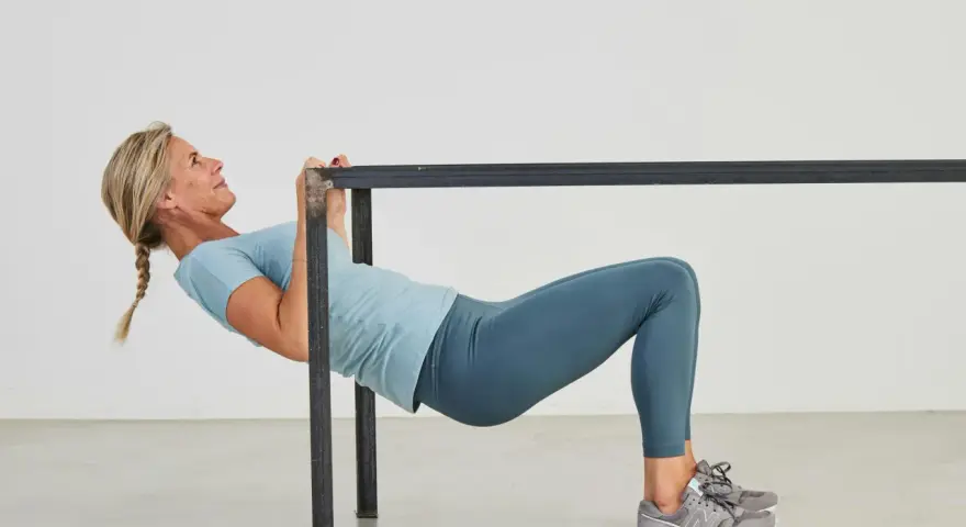 Kvinna utför overhead triceps extension vid en ställning.