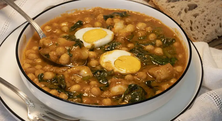 Potaje de garbanzos con bacalao y huevo duro en un cuenco blanco.