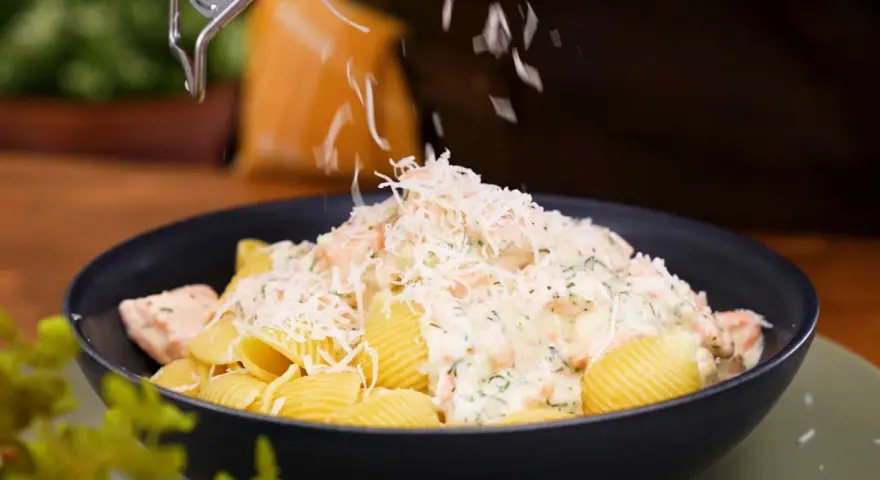 En krämig lax pasta med crème fraîche toppas med riven ost.