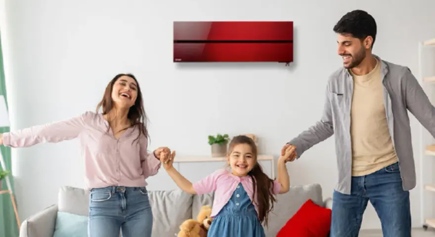 Familia feliz bailando en una sala con aire acondicionado inverter rojo. Disfrutan del confort y bajo consumo kwh.