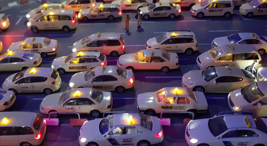 Modellautos von Taxis stehen im Stau. Die Lichter leuchten, als ob sie Nachtzuschlag berechnen würden.