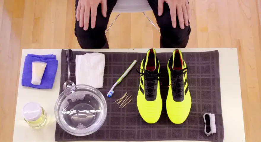 Kit per pulire le scarpe Adidas gialle: spazzolino, acqua saponata, panni e crema.